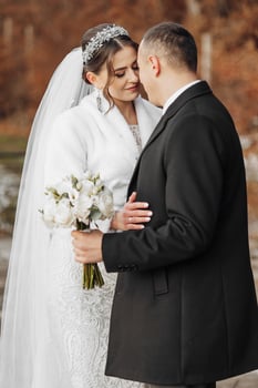 A bride and groom are embracing each other with a bouquet of white flowers in the bride's hand photo