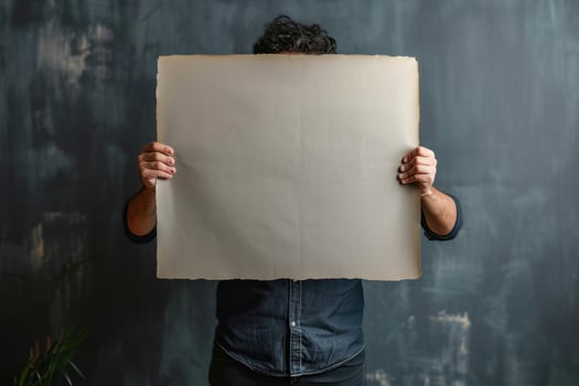 a man holding up an old paper while standing near a plant, photo
