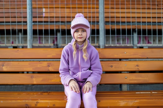 the girl is sitting on a bench wearing purple, photo