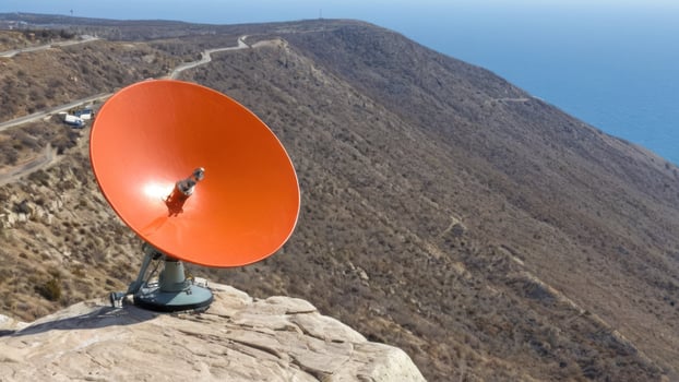 an orange dish atop top of a mountain next to the ocean, photo