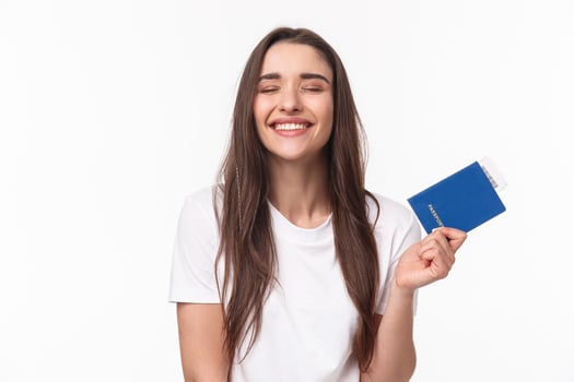 Travelling, holidays, summer concept. Dreamy happy young beautiful girl in white t-shirt, close eyes smiling, daydreaming how she sunbathing near beach on vacation, hold passport with ticket photo