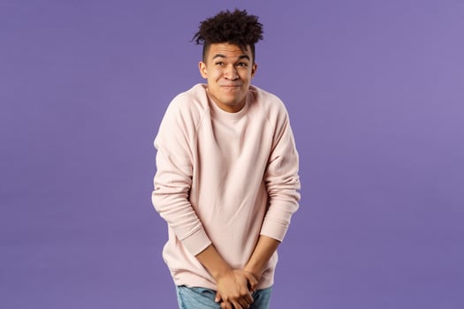 Portrait of young man need to pee, cant hold it looking at clock while standing in line, being in queue to toilet, drank too much water, standing with discomfort hold hands on pants photo