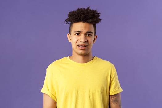 Waist-up portrait of young concerned hispanic man with worried gaze looking at camera, frowning being scared for friend stuck in troublesome situation, want help, stand purple background photo