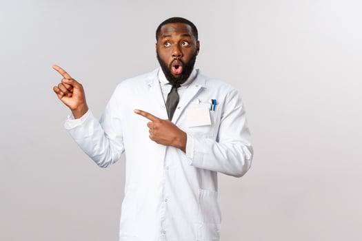 Covid19, healthcare and clinic concept. Impressed, speechless african-american male doctor gossiping with nurses at hospital, say wow, look and pointing upper left corner astounded, stand in awe photo