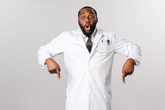 Healthcare, insurance and clinic concept. Amazed, excited african-american doctor telling to hurry up and look down, pointing fingers at bottom, medical product, breaking news photo