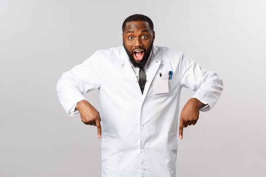 Healthcare, insurance and clinic concept. Excited, happy african american doctor in white coat, pointing fingers down and look camera with fascinated amused smile, tell hurry and click the link photo