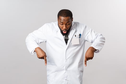 Healthcare, insurance and clinic concept. Amazed and excited african-american doctor in white coat, gasping amused, looking and pointing fingers down at awesome product, great quality, recommend photo