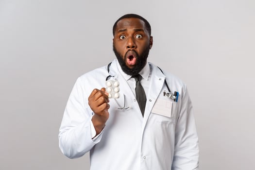Flu, disease, healthcare and medicine concept. Shocked african-american doctor realise patient took pills wrong, didnt follow prescribtion, drop jaw gasping and holding medication, grey background photo