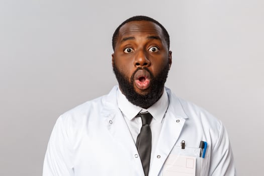 Healthcare, medicine and hospital treatment concept. Close-up portrait of shocked and speechless african-american doctor, physician gasp and startled staring camera, standing astonished photo