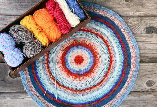 Knitted mat and colorful skeins of wollen yarn photo