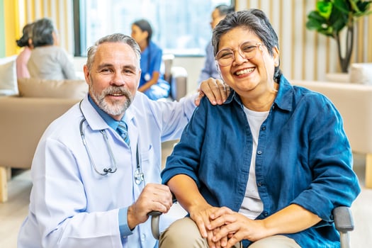 Portrait of Happy Asian disabled Senior Elderly female on wheelchair enjoy stay home nursing care. caucasian doctor caregiver sit beside older patient, looking at camera. medical insurance concept. photo