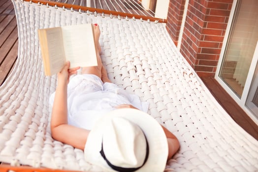 Woman lying in hammock and reading book photo
