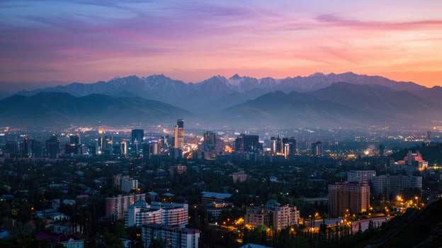 An expansive view of Almaty's cityscape at dusk with vibrant lights and mountains visible. photo