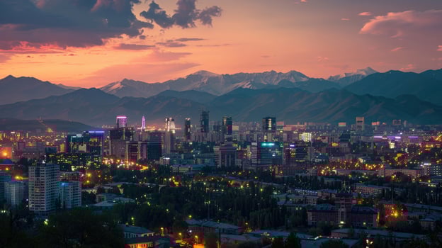 An expansive view of Almaty's cityscape at dusk with vibrant lights and mountains visible. photo