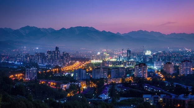 An expansive view of Almaty's cityscape at dusk with vibrant lights and mountains visible. photo