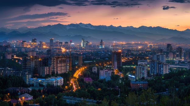 An expansive view of Almaty's cityscape at dusk with vibrant lights and mountains visible. photo