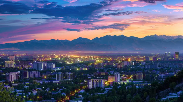 An expansive view of Almaty's cityscape at dusk with vibrant lights and mountains visible. photo