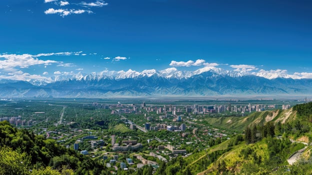 A sweeping view of Almaty with snow-capped mountains in the distance on a bright sunny day. photo