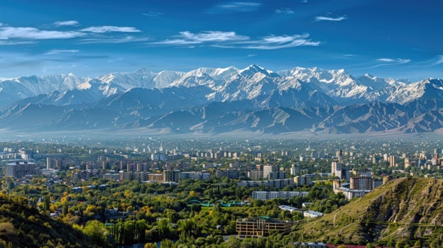 A sweeping view of Almaty with snow-capped mountains in the distance on a bright sunny day. photo