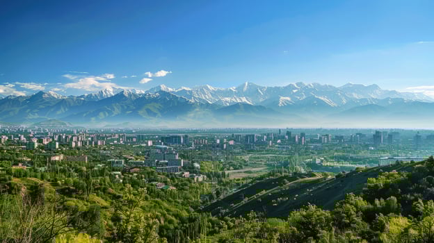 A sweeping view of Almaty with snow-capped mountains in the distance on a bright sunny day. photo