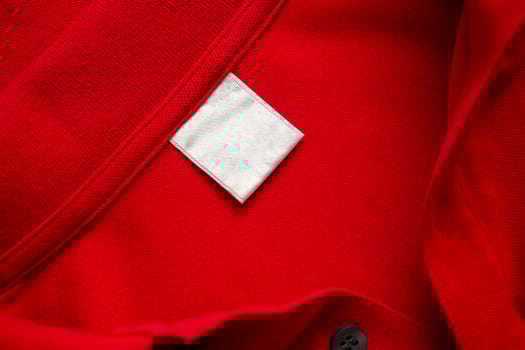 Blank white laundry care clothes label on red shirt fabric texture background photo