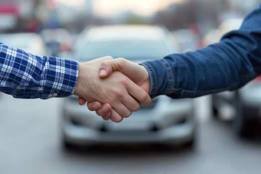men shaking hands after a successful deal to sell a car in a car parking lot, a car in the background photo
