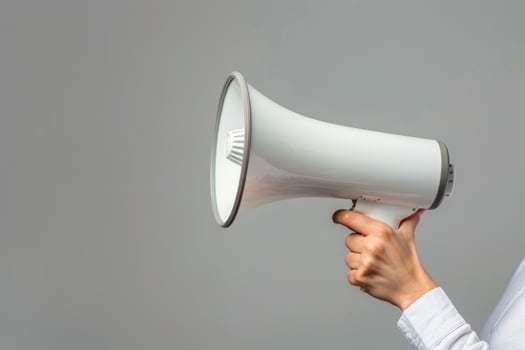 Hand holding a megaphone on a gray background photo