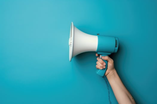 Hand holding a blue and white megaphone against a blue background photo