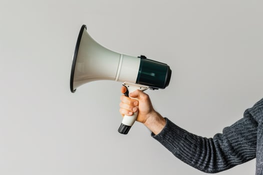 Hand holding a megaphone on a neutral background photo