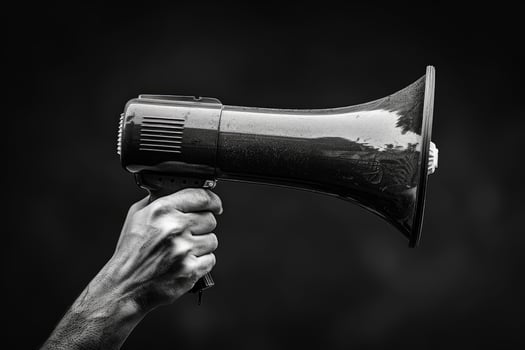 Hand holding a megaphone with a dark background photo