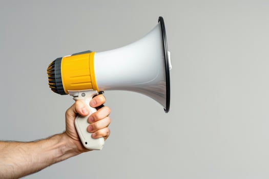 Hand holding a megaphone on a gray background photo