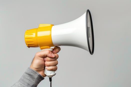 Hand holding a yellow and white megaphone on a gray background photo