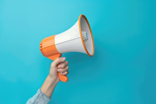 Hand holding a megaphone against blue background photo