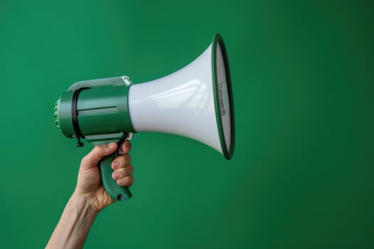 Hand holding a megaphone against a green cracked wall background photo
