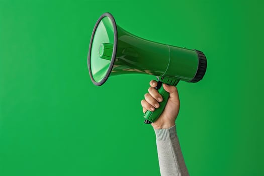 Hand holding a green megaphone on a green background photo