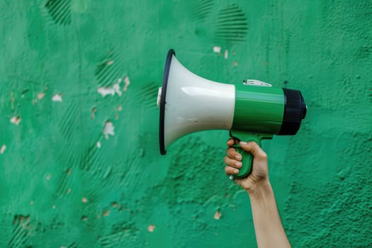 Hand holding a megaphone against a green cracked wall background photo