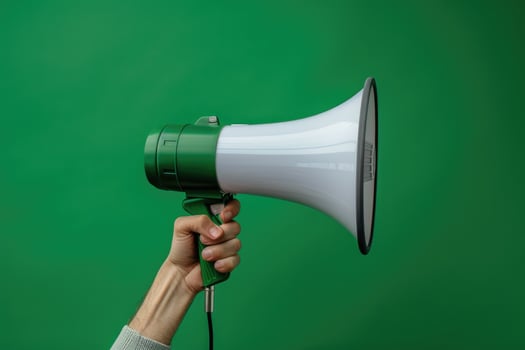 Hand holding a megaphone against a green cracked wall background photo