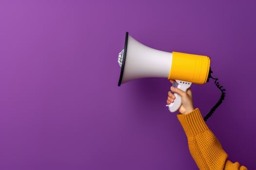 Hand holding a megaphone against purple background photo