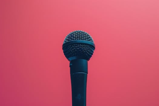 Closeup of a black microphone against a pink background photo