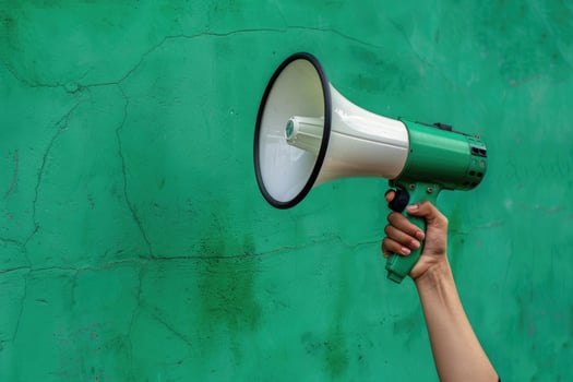 Hand holding a megaphone against a green cracked wall background photo