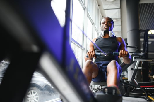 Motivated young black sportsman having workout on rowing machine photo