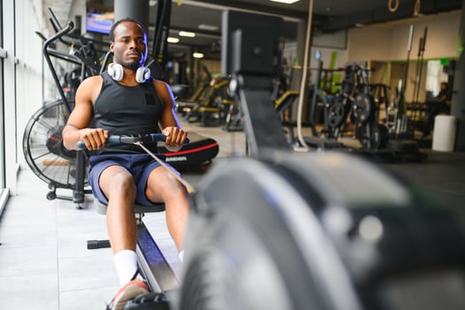 Motivated young black sportsman having workout on rowing machine photo