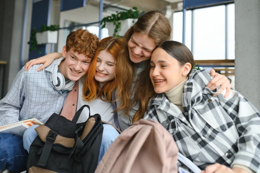 A group of cheerful student friends are sitting on the floor in a classroom photo