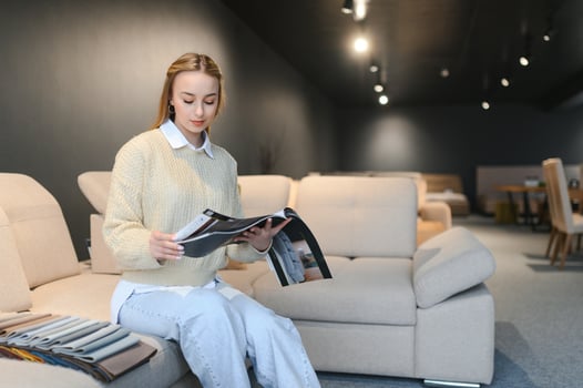 Happy young woman chooses sofa for home in furniture store photo