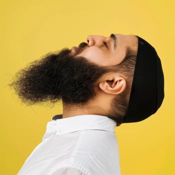 Muslim Man With a Beautiful Beard Posing Against a Yellow Background photo