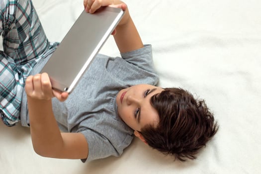 Portrait of teenage boy lies on his back hold digital tablet photo