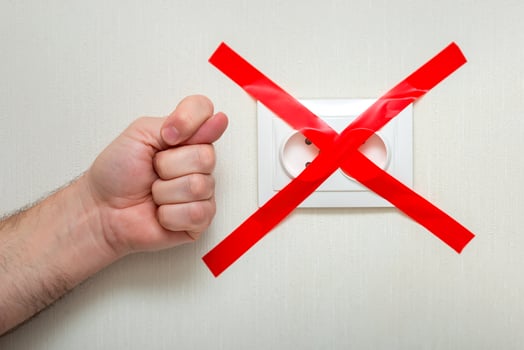 The man shows a fig gesture near the electrical outlet, tied with a red ribbon criss-cross. photo