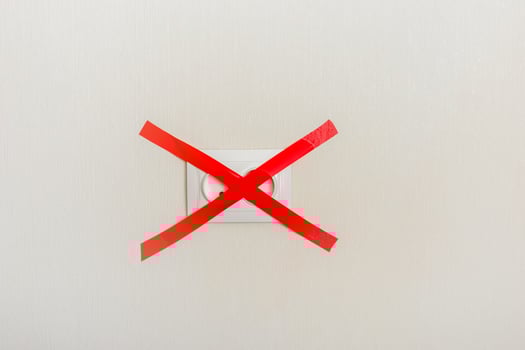 Electrical outlet, on a light wall, covered with a red ribbon cross to cross photo