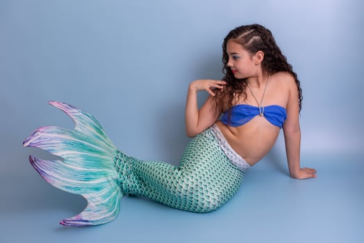 Beautiful elegant girl in a mermaid costume, isolated on a blue background. photo