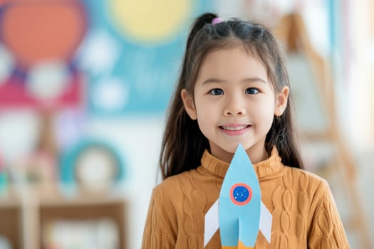 Smiling Girl Holding Paper Rocket photo